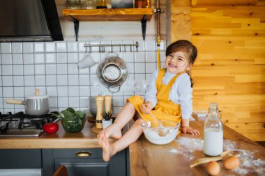 Sevimli küçük kız mutfakta gülüyor.