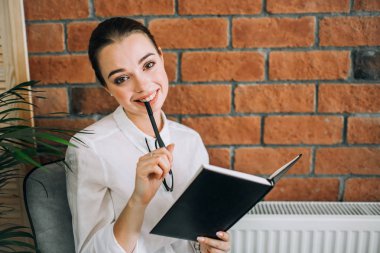 Not defteri ve kalem ile mutlu genç kadın.