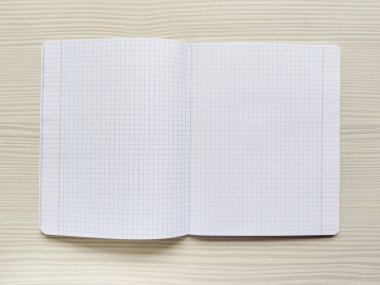 Kafesteki beyaz okul defteri ahşap bir masanın üzerinde. Boş not defteri bir masanın üzerindedir. Notsuz egzersiz kitabı. Damalı arka plan. Kare doku