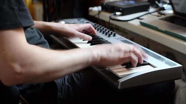 Ein weißer Mann im schwarzen T-Shirt spielt seine Lieblingsmusik auf einem Synthesizer — Stockvideo