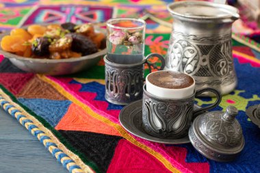 Otantik fincanda kahve ve kuru meyveli el yapımı halıda su.