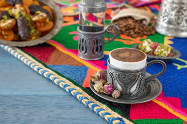 Otantik fincanda kahve ve kuru meyveli el yapımı halıda su.