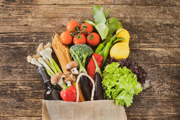 Masadaki alışveriş poşetinde bir sürü sebze ve meyve var.