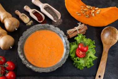 Siyah masa arkasında domates ve baharatlı balkabağı kremalı çorba.