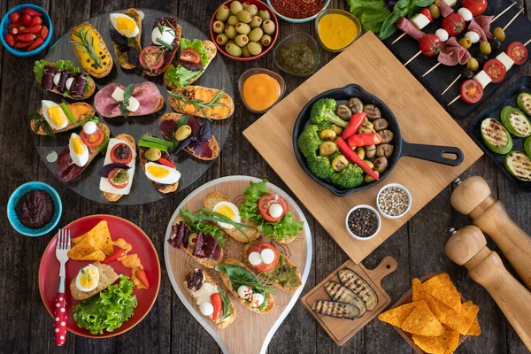 Köy ahşap masada siyah arka planda bir sürü tapas var. Üst Düzey Akdeniz Gıda Konsepti.