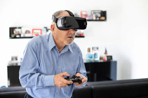 Elderly joyful man plays soccer with virtual reality goggles , new technologies concept with vr glasses