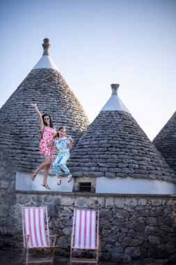 Bir anne kızıyla birlikte Trulli evlerinin önüne atlıyor. Aile konseptiyle eğleniyorum..