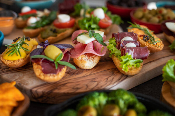 Many tapas on the rustic wooden table with black background. Top view mediterian food concept.