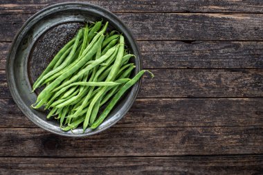 Ahşap kırsal masada bir sürü yeşil fasulye var. Taze sebze konsepti. 