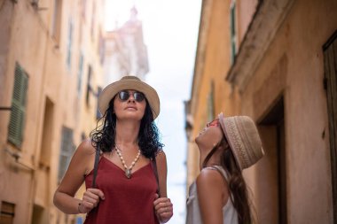 Turist kadın, Korsika 'nın dar sokaklarında kızıyla birlikte yürüyor ve keşfediyor..