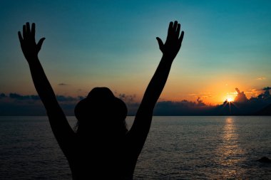 Cinque Terre 'de gün batımında kaygısız bir kadın silueti, günbatımı konsepti ve elleri havada bir kadın.