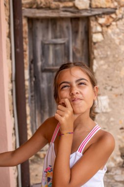 Beyaz taş bir duvarın önünde gülen sevimli bir kızın portresi. Bir liseli kızın yan görüş konsepti. 