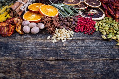 Ahşap kırsal masada birçok renkli baharatlar, otlar ve kurutulmuş meyveler. Kaşıklar ve kâselerdeki baharatlar.. 