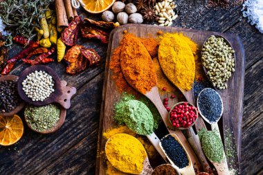 Ahşap kırsal masada birçok renkli baharatlar, otlar ve kurutulmuş meyveler. Kaşıklar ve kâselerdeki baharatlar.. 
