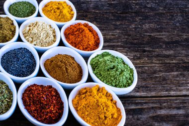 Ahşap kırsal masada birçok renkli baharatlar, otlar ve kurutulmuş meyveler. Kaşıklar ve kâselerdeki baharatlar.. 