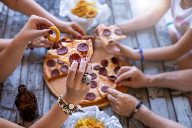 Birçok el pizza dilimiyle masada. Pepperonili pizza ile fast food konsepti.