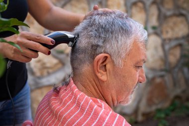 Corona virüsü yüzünden evde saç kesme konsepti. Bir kadın babasının saçını kesiyor..