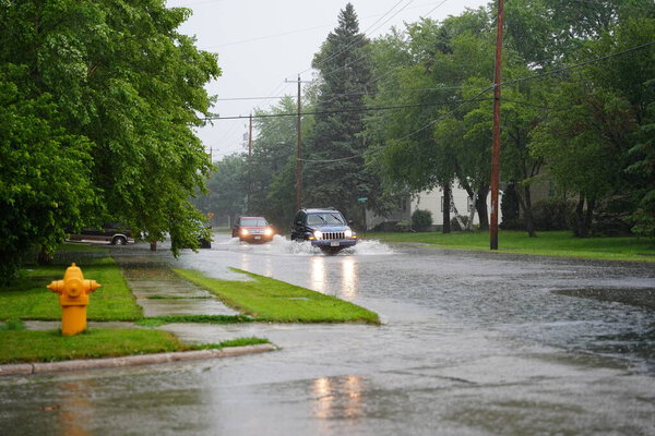 Fond du Lac, Wisconsin / USA - July 10th, 2020: Citizens of Fond du Lac drive through the flooded streets in their vehicles from the huge downpour of rain during the afternoon in july 2020.