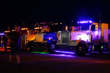 Waupun, Wisconsin ABD - 11 Ağustos 2023: Büyük kamyonlar ve yarı kamyonlar gece boyunca sarı uyarı ışıkları açık parladı.