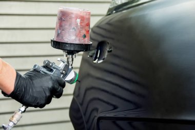 a car painter paints the fender of a car clipart