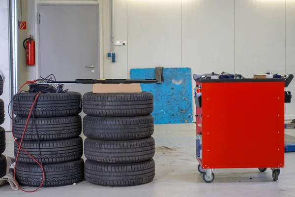Dos pilas de neumáticos de coche y un carro de herramientas —  Fotos de Stock