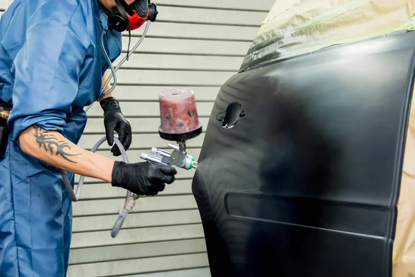 Un pintor de coches pinta el guardabarros de un coche — Foto de Stock