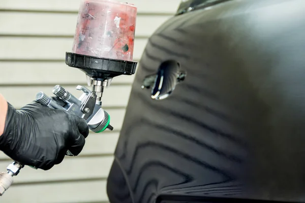 a car painter paints the fender of a car