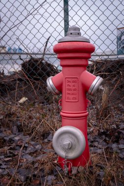 bir kırmızı musluğu bir çit önünde duruyor