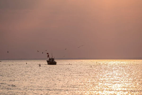 Um barco no mar ao nascer do sol — Fotografia de Stock