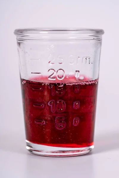 Un vaso lleno de medicamento rojo —  Fotos de Stock