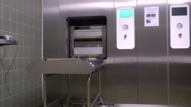 bir sterilizatör kapısını açar ve içeriğini otomatik olarak boşaltır