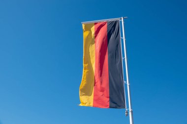 mavi bir gökyüzünün önünde bir Alman bayrağı eser