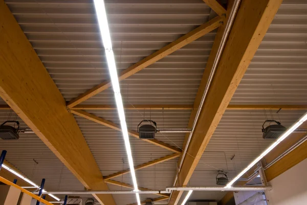 Large wooden trusses support the roof of a large factory buildin