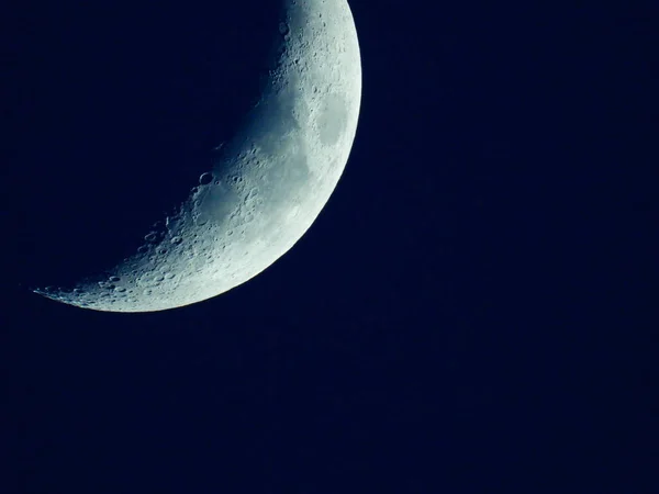 Un cuarto de luna naciente en el cielo azul oscuro de la tarde — Foto de Stock