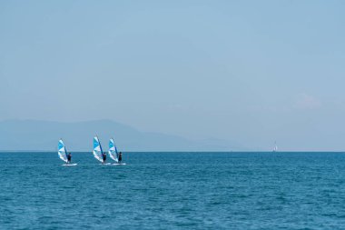 Üç rüzgar sörfçü deniz tarafında yan yüz