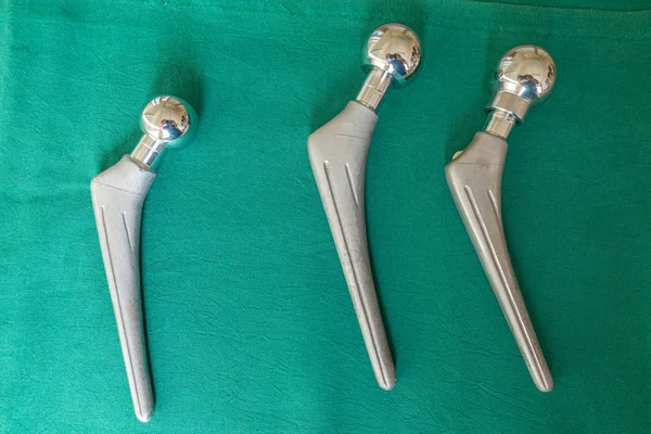 Explanted hip prostheses lie spread out on a green surgical drap — Stock Photo, Image