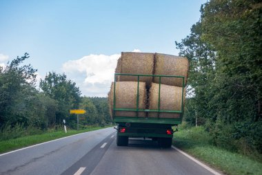 birkaç saman balyaları ile yüklü bir traktör bir ülke üzerinde sürücüler 