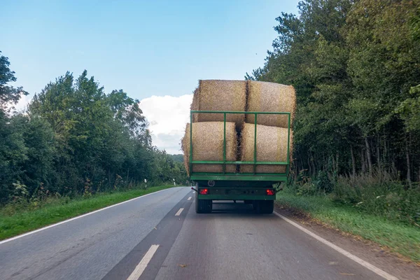 a tractor loaded with several straw bales drives over a country