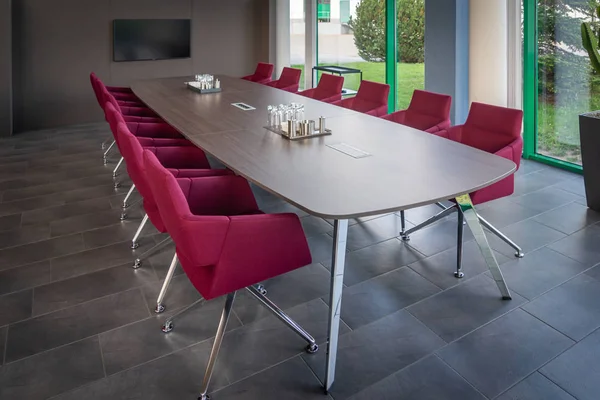 A brown conference table is surrounded by red armchairs and in t — Stock Photo, Image