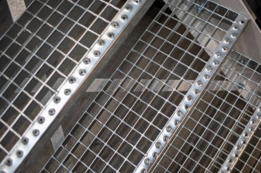 Bir fabrika salonunda metal bir zemin ve merdivenler bulunmaktadır.