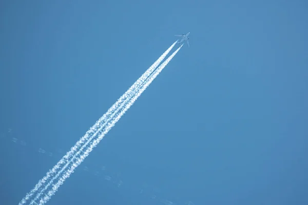 En el cielo azul un gran avión de pasajeros vuela y deja atrás tw —  Fotos de Stock