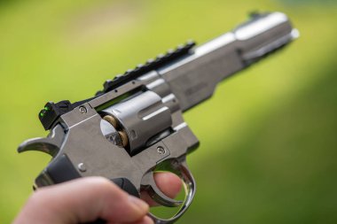 bir elinde büyük gümüş ağır tabanca ve havaya hedefliyor