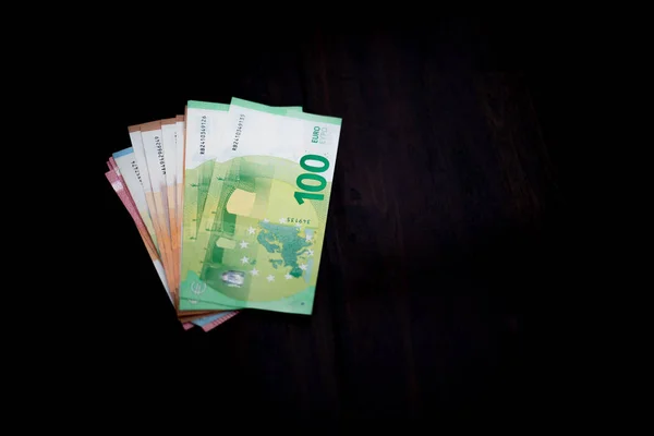 Un sacco di banconote in euro stese su un tavolo scuro — Foto Stock