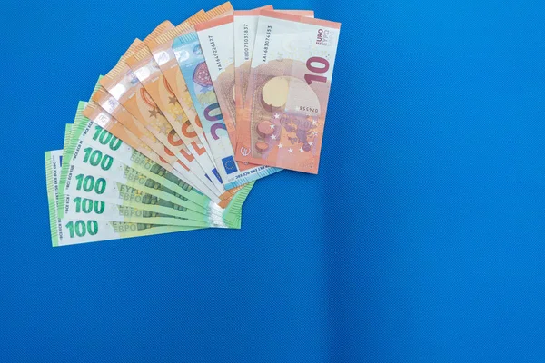 Veel eurobankbiljetten liggen verspreid op een blauwe basis — Stockfoto