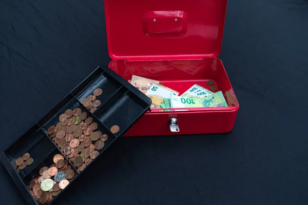 Viele Euro-Banknoten liegen ausgebreitet in roter Kasse — Stockfoto