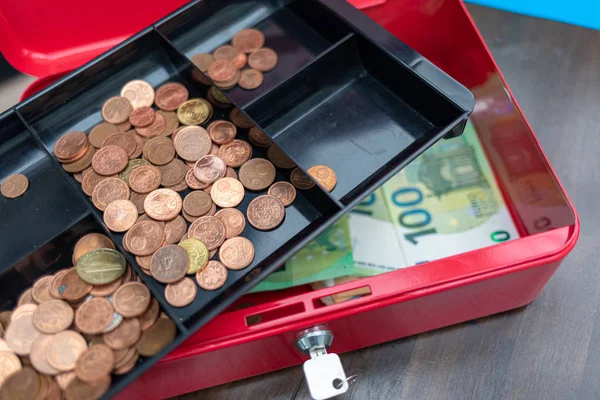 Um monte de notas de euro estão espalhadas em uma caixa de caixa vermelha — Fotografia de Stock