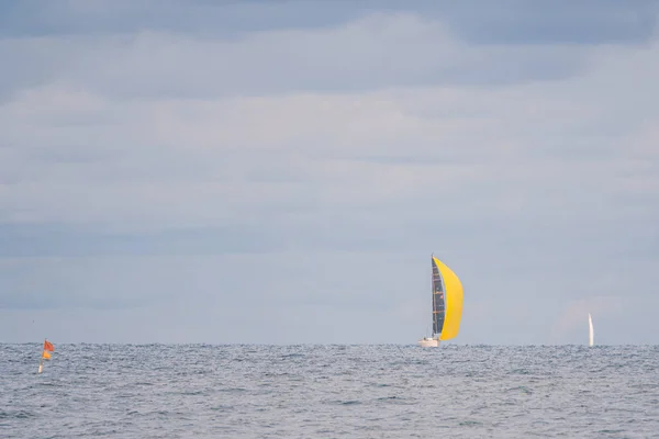 Daleko na moři plave plachetnice s jasně žlutou plachtou a t — Stock fotografie