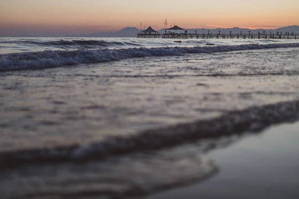 En una playa en primer plano están las olas y en el fondo — Foto de Stock