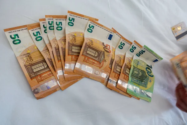 许多欧元钞票铺在铺有白色羽绒被的床上 — 图库照片