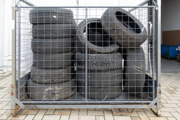 Muchos neumáticos viejos se apilan frente a un garaje para ser desechados . —  Fotos de Stock